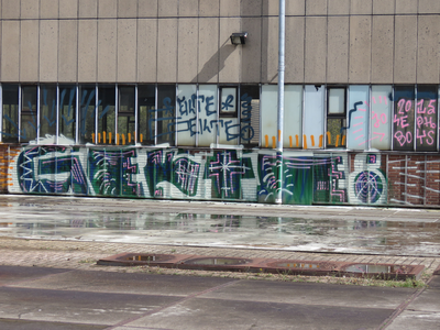 829802 Afbeelding van graffiti met veel teksten, op de gevel van een voormalige werkplaats van de N.S. op het terrein ...